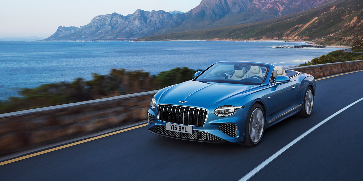 Bentley Leusden New Bentley Continental GTC Azure convertible in Light Windsor blue paint with 22 inch Azure wheels and chrome grill, driving dynamically by the sea