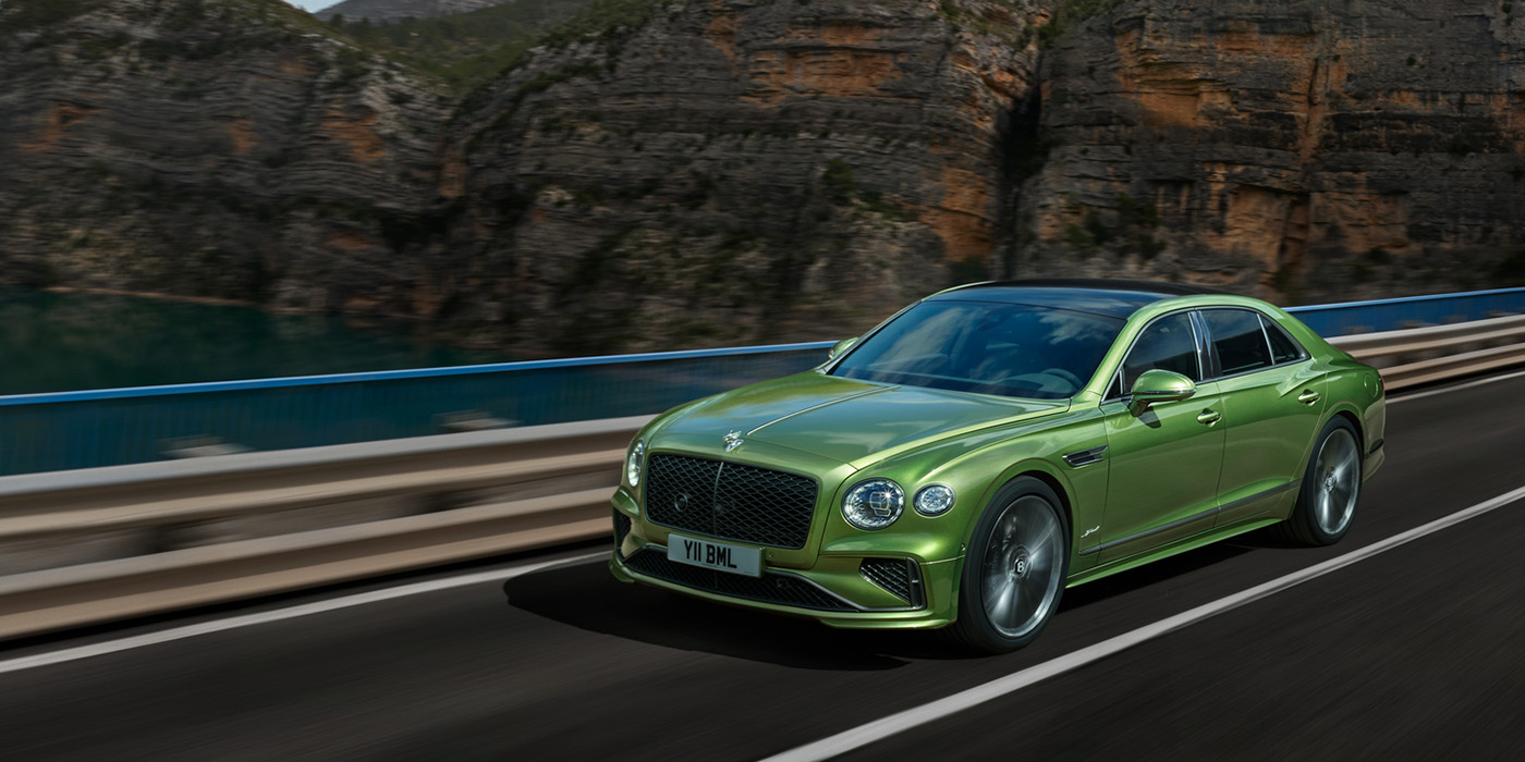 Bentley Leusden Bentley New Flying Spur Speed v8 hybrid sedan driving dynamically on a mountain road in Tourmaline Green paint