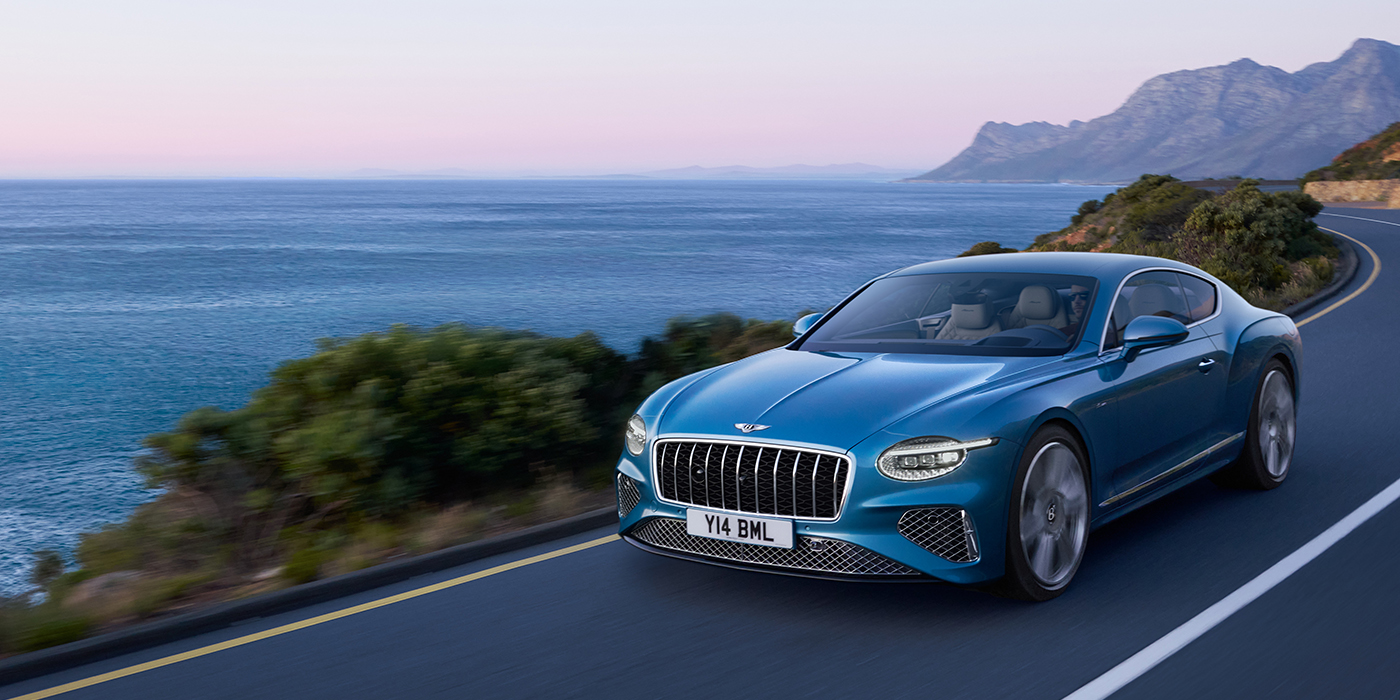 Bentley Leusden New Bentley Continental GT Azure coupe in Light Windsor blue paint with 22 inch Azure wheels and chrome grill, driving dynamically by the sea