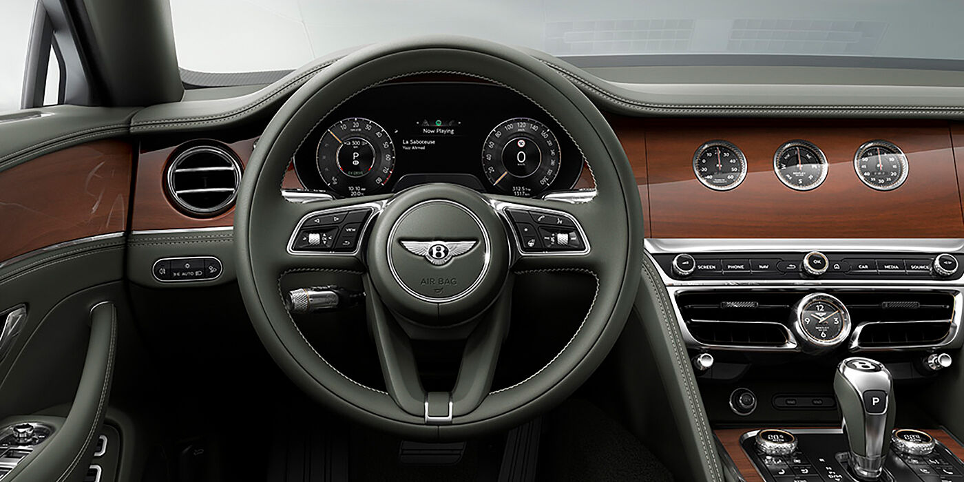 Bentley Leusden New Bentley Flying Spur sedan front cabin in Cumbrian Green hide and Crown Cut walnut veneer showing steering wheel and Rotating Display with three clocks on face
